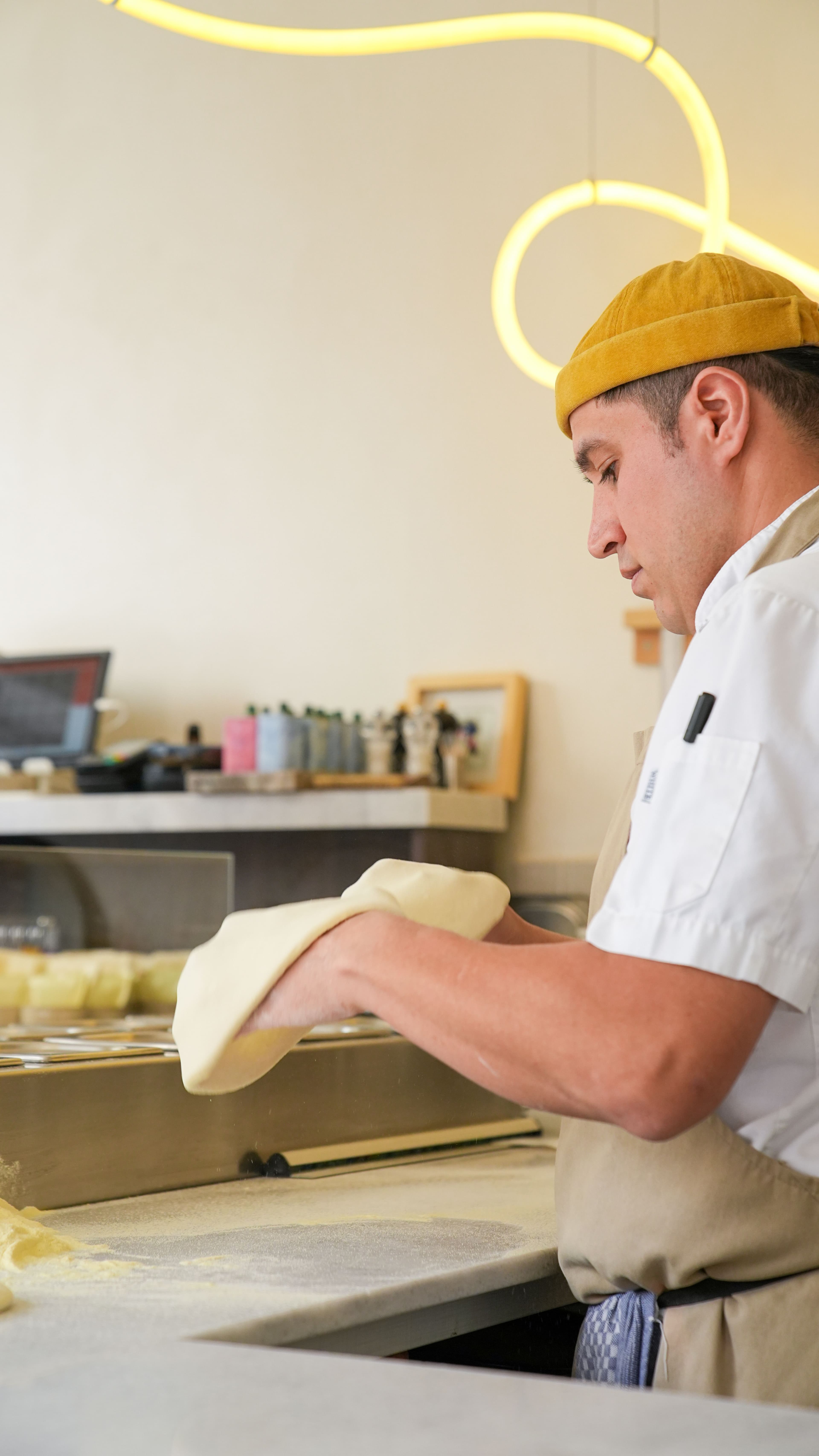 Baker scoring a flour-dusted sourdough loaf by hand